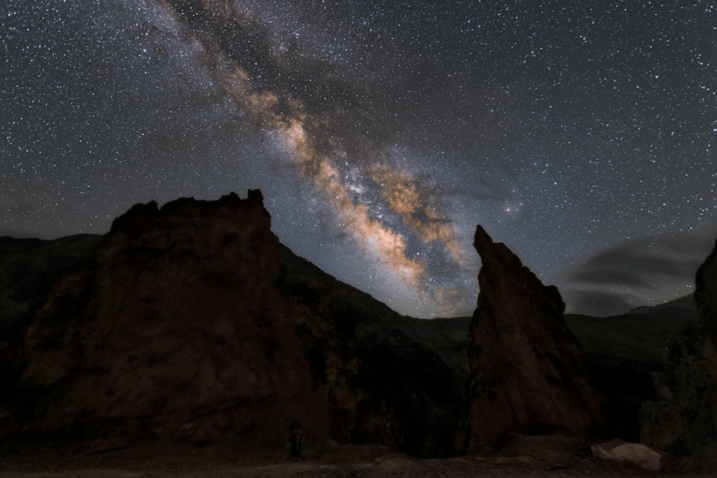 Milky Way galaxy arch above jagged rock formations, offering a striking backdrop for the Drake equation.
