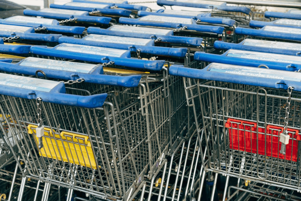 Row of blue-handled shopping carts with coin-lock chains at a supermarket entrance.
