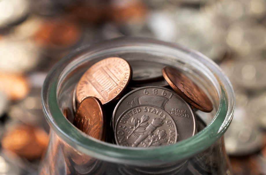 Close-up of U.S. pennies and quarters in a glass jar.