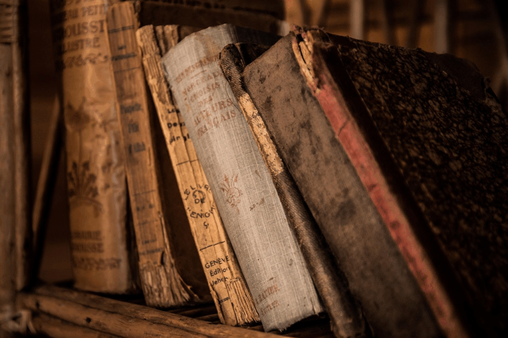 Close-up of worn antique books lined on a wooden shelf, evoking the history of everyday phrases.