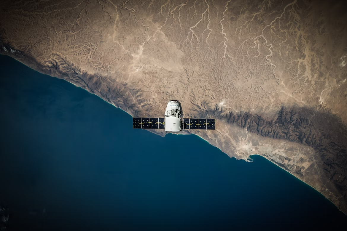 Low-orbit satellite over a desert coastline, illustrating GPS and communications infrastructure from space.
