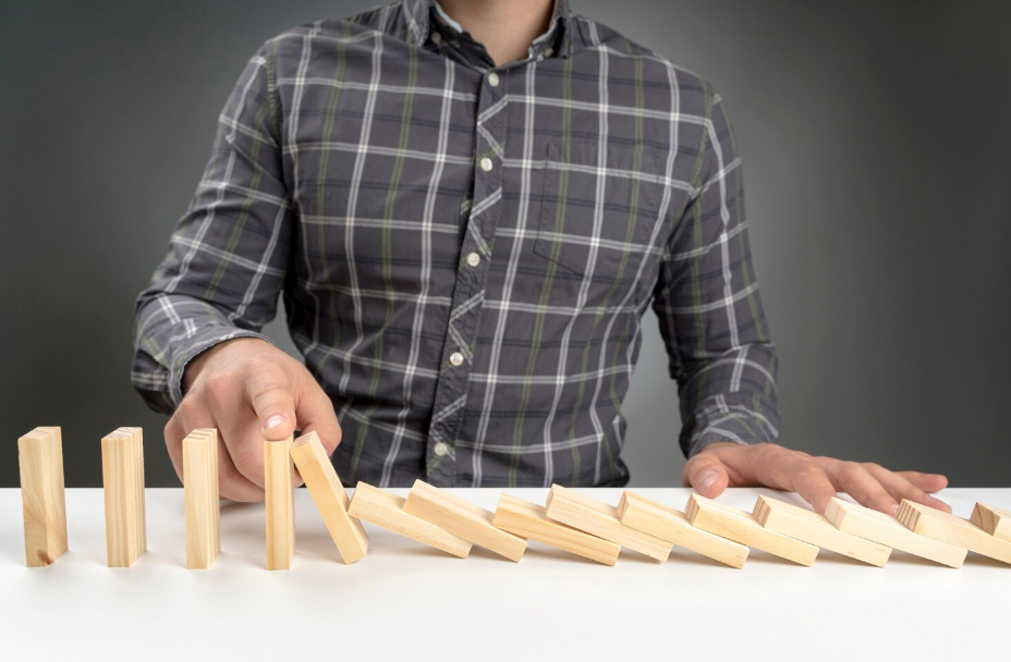 Close-up of a person tipping wooden dominoes to start a satisfying chain reaction.