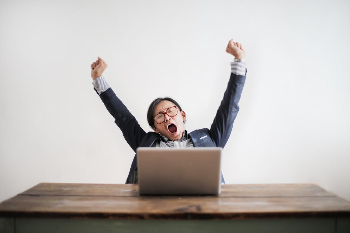 Office worker yawning with arms raised, illustrating contagious yawning and workplace fatigue.