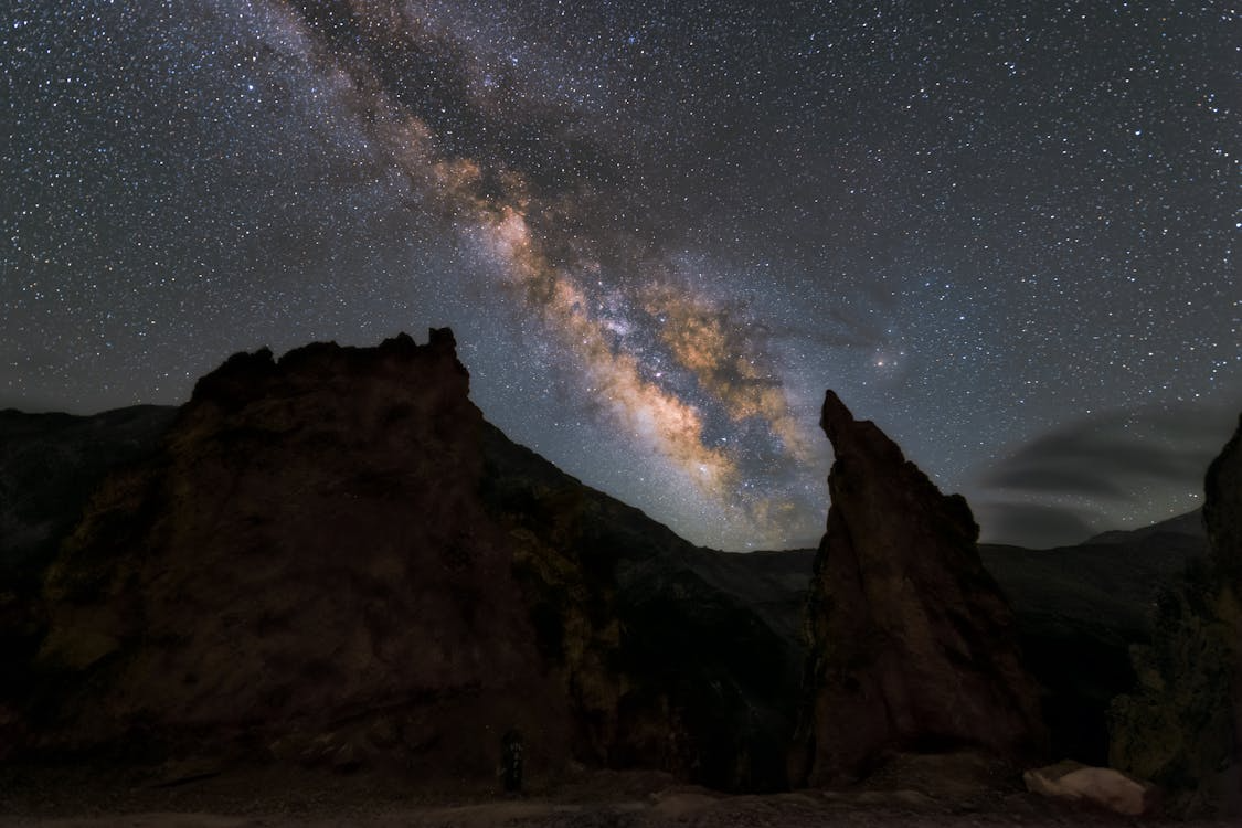 Milky Way galaxy arch above jagged rock formations, offering a striking backdrop for the Drake equation.